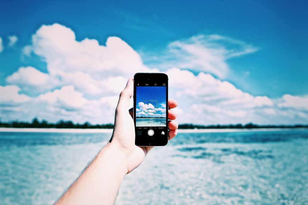 An image showing a smartphone, sea and clouds.