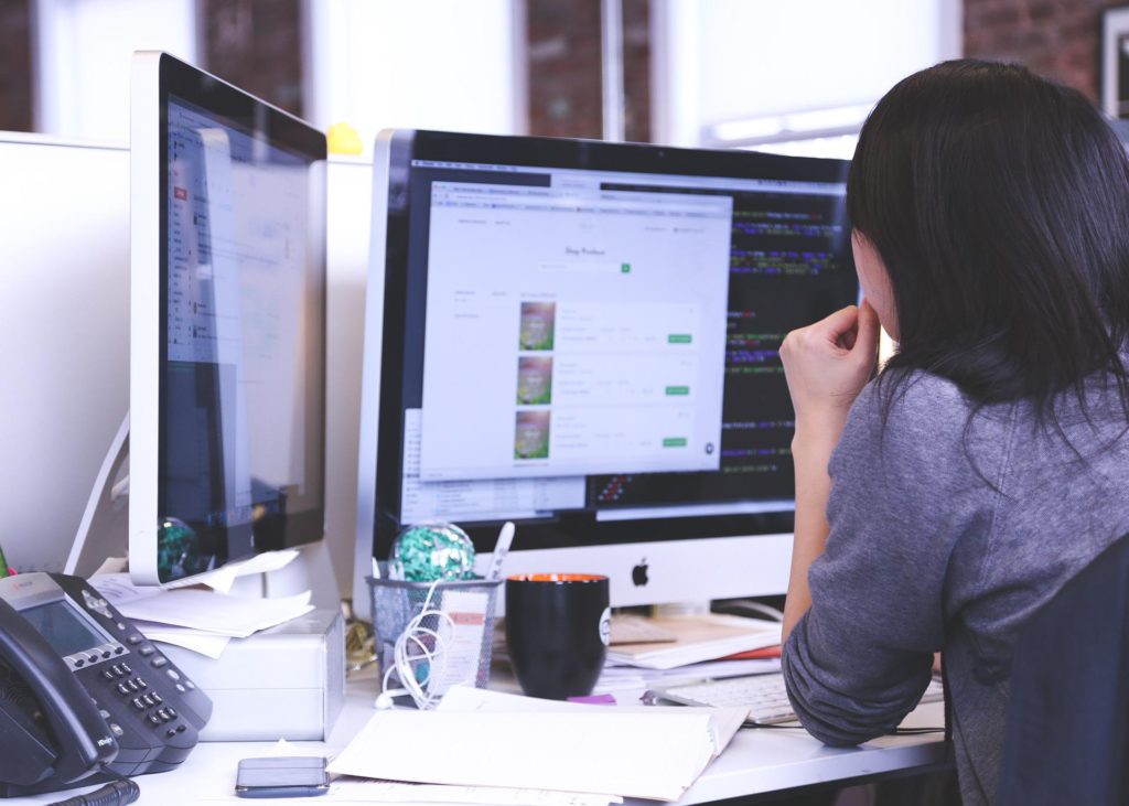 A photo showing a woman behind a computer.